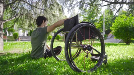 Junger-Behinderter-Mensch-Schaut-Auf-Seinen-Rollstuhl.